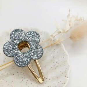 Barrette Fleur Argenté en résine brillante posée sur fond clair, accessoire cheveux fait main en Bretagne