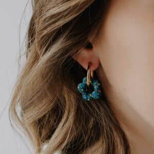Créoles Oia Bleuet dorées avec fleur en résine bleu intense portées à l’oreille