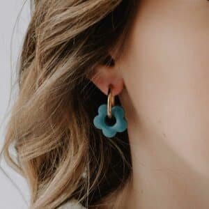 Créoles Oia Cyanéa dorées avec pendentif fleur en résine bleu océan portées à l’oreille