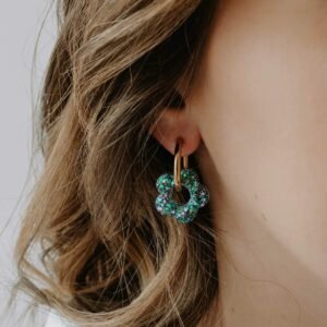 Créoles Oia Myosotis dorées avec fleur en résine bleu ciel posées sur fond clair