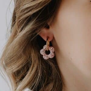 Créoles Oia Silène dorées avec fleur en résine rose fuchsia portées à l’oreille