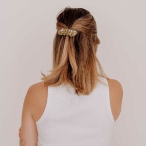 Femme portant la Barrette Honfleur en tissu vert brodé, fixée dans ses cheveux.