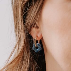 Boucles d’oreilles Créoles Mini Oia - Irisia en résine bleue pailletée et anneau doré portées à l’oreille