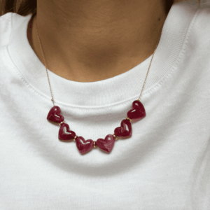 Collier Love - Grenat avec cœurs en résine marbrée grenat montés sur une chaîne dorée fine, porté autour du cou.