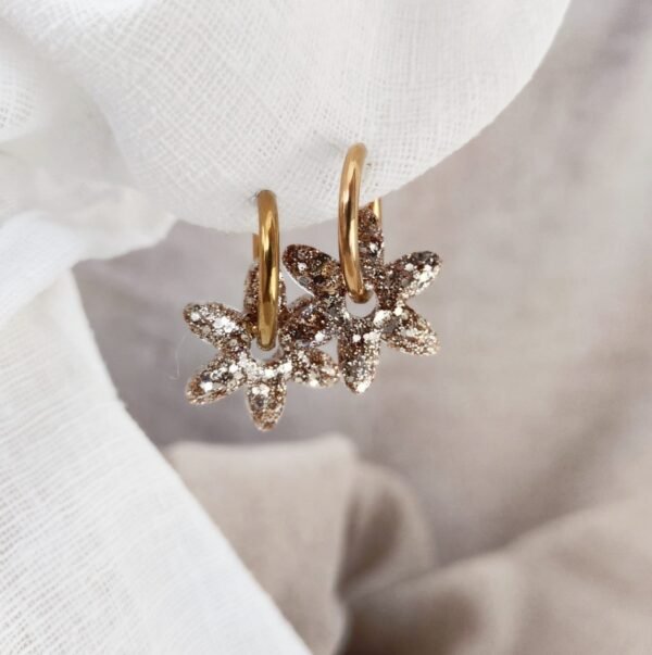 Créoles Noosa doré fleurs résine élégantes - Atelier R. Créoles Noosa doré avec fleurs en résine scintillante montées sur anneaux en acier inoxydable